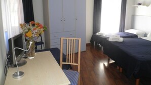 Une chambre d’hôtel équipée d’un bureau, d’une chaise, d’une armoire, de deux lits et d’une table de chevet.