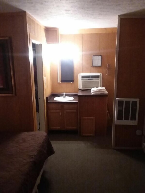 A compact room with a bed, a small sink, and a window.