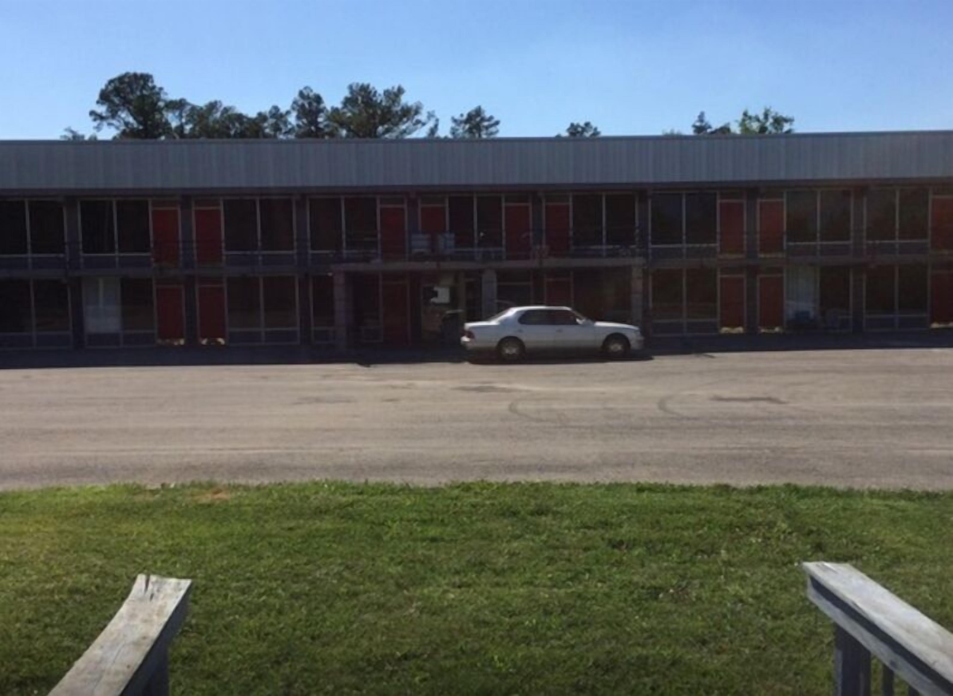 A building with a parking lot and a white car parked in front.