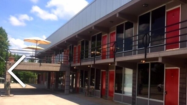 A modern building with multiple floors, large windows, and red doors. - The Resort (Falls of Rough)