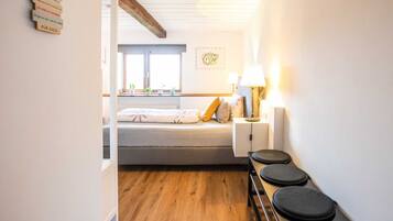 Ein Schlafzimmer mit Bett, Nachttisch, Lampe und Blick nach draußen.