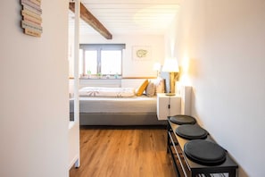 Un dormitorio con cama, mesita de noche, lámpara y vistas al exterior.
