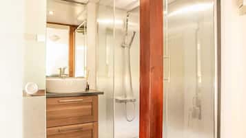 A modern bathroom with a glass-enclosed shower, wooden vanity, and a large mirror.