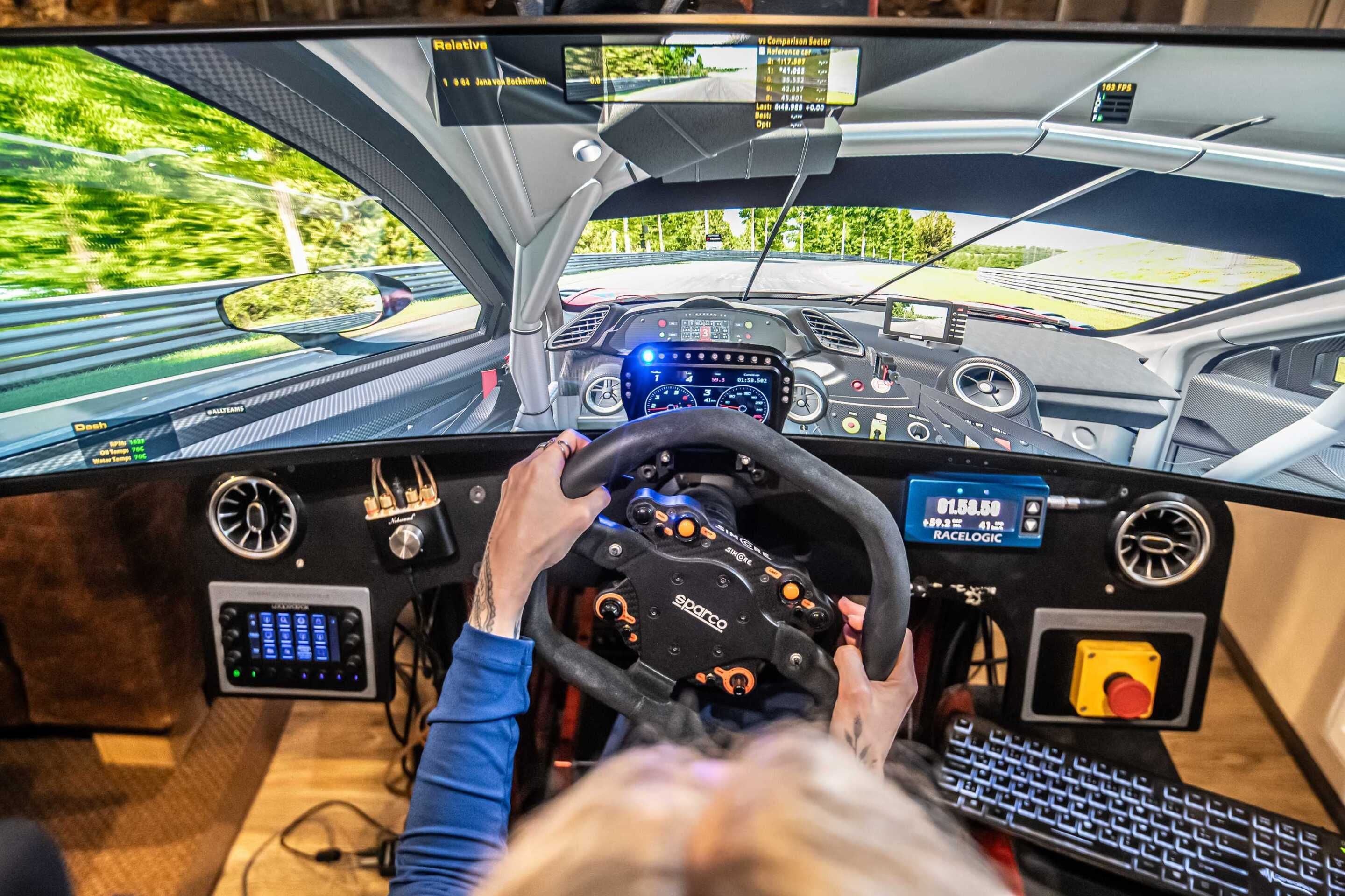 Een rijsimulator met stuur, dashboard en meerdere schermen waarop een virtuele rijomgeving wordt getoond.