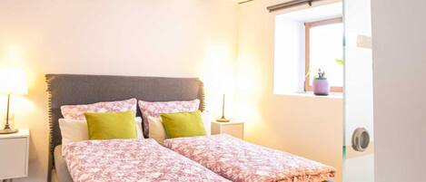 Un dormitorio con cama, lámparas de noche y ventana.
