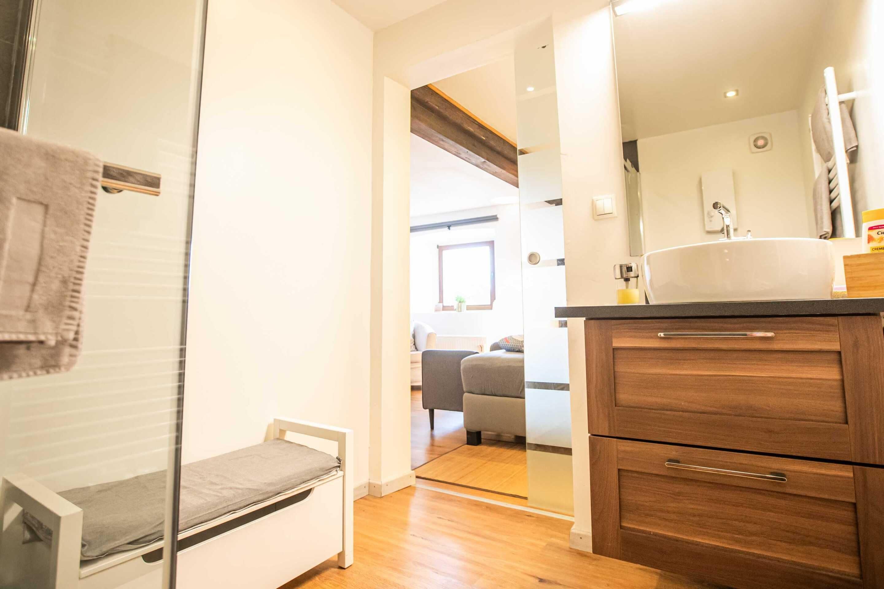 Un baño con tocador de madera, espejo y lavamanos.