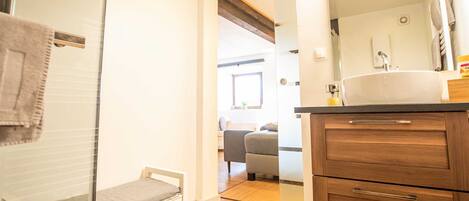 A bathroom with a wooden vanity, a mirror, and a sink.