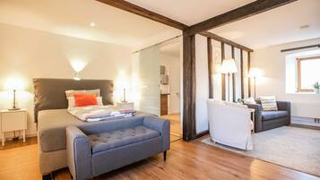 Un dormitorio moderno con cama, un sillón gris, un sofá y una ventana.