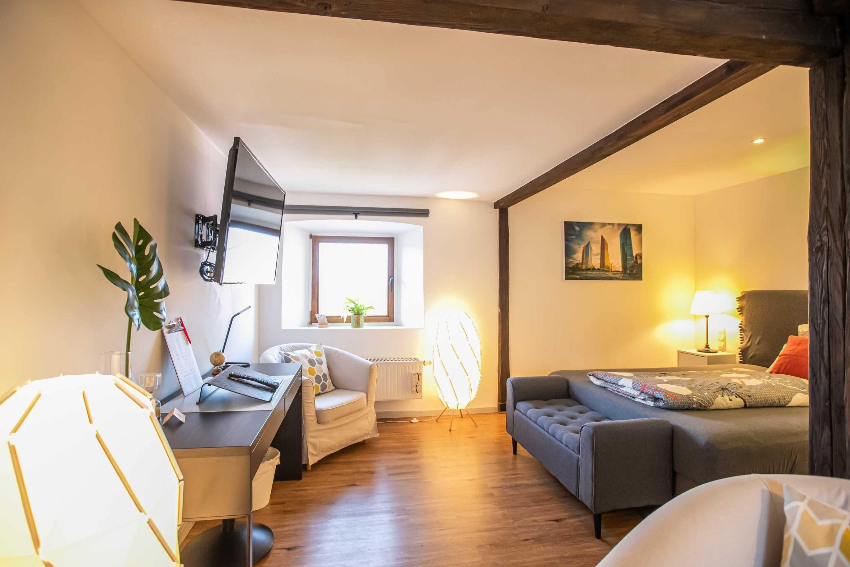 Una sala de estar moderna con un escritorio, un sofá, una lámpara de pie y un cuadro en la pared.