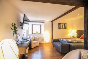A modern living room with a desk, a sofa, a standing lamp, and a painting on the wall. - Pension Schwedenkreuz (Reimerath)