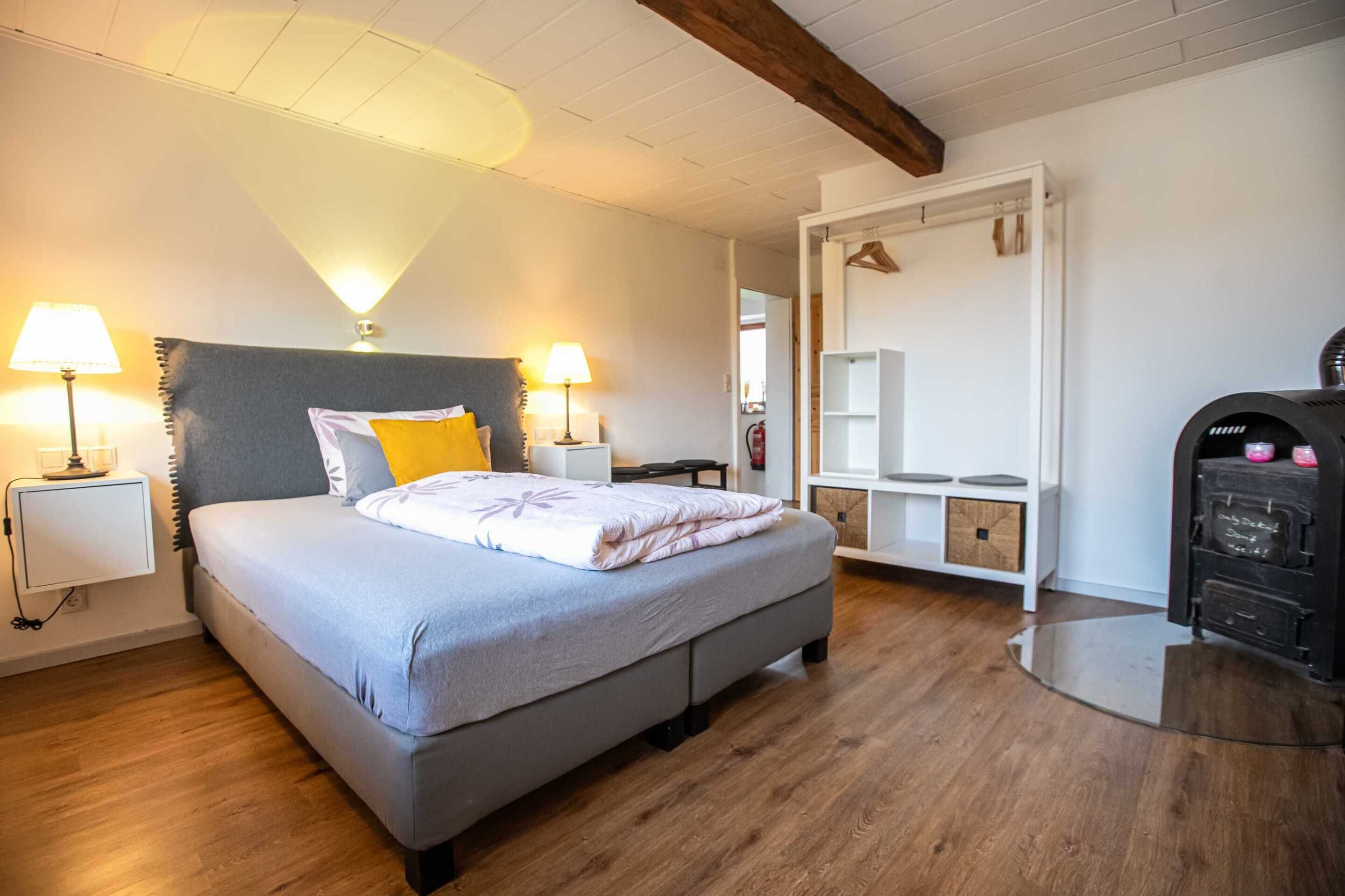 Een slaapkamer met een bed, nachtlampjes, een kledingkast en een bureau.