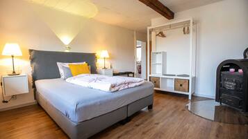 Een slaapkamer met een bed, nachtlampjes, een kledingkast en een bureau.