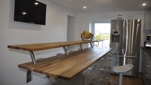 A modern kitchen with a wooden bench, stainless steel appliances, and a flat-screen TV. - Pension Schwedenkreuz (Reimerath)