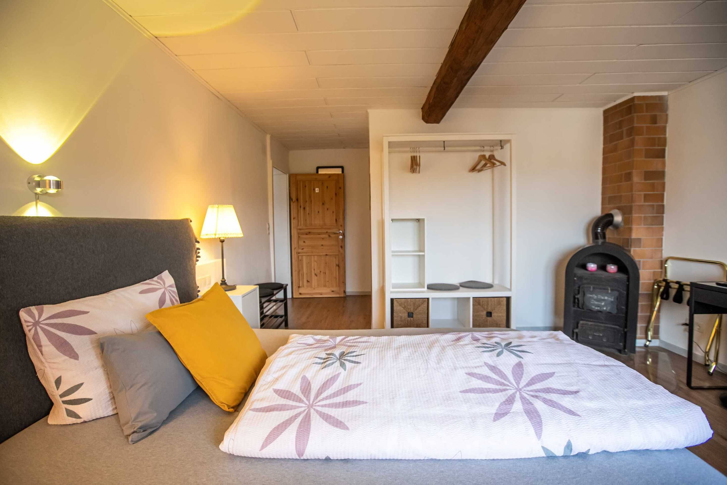 A bedroom with a bed, bedside lamps, a wardrobe, a mirror, and a fireplace.