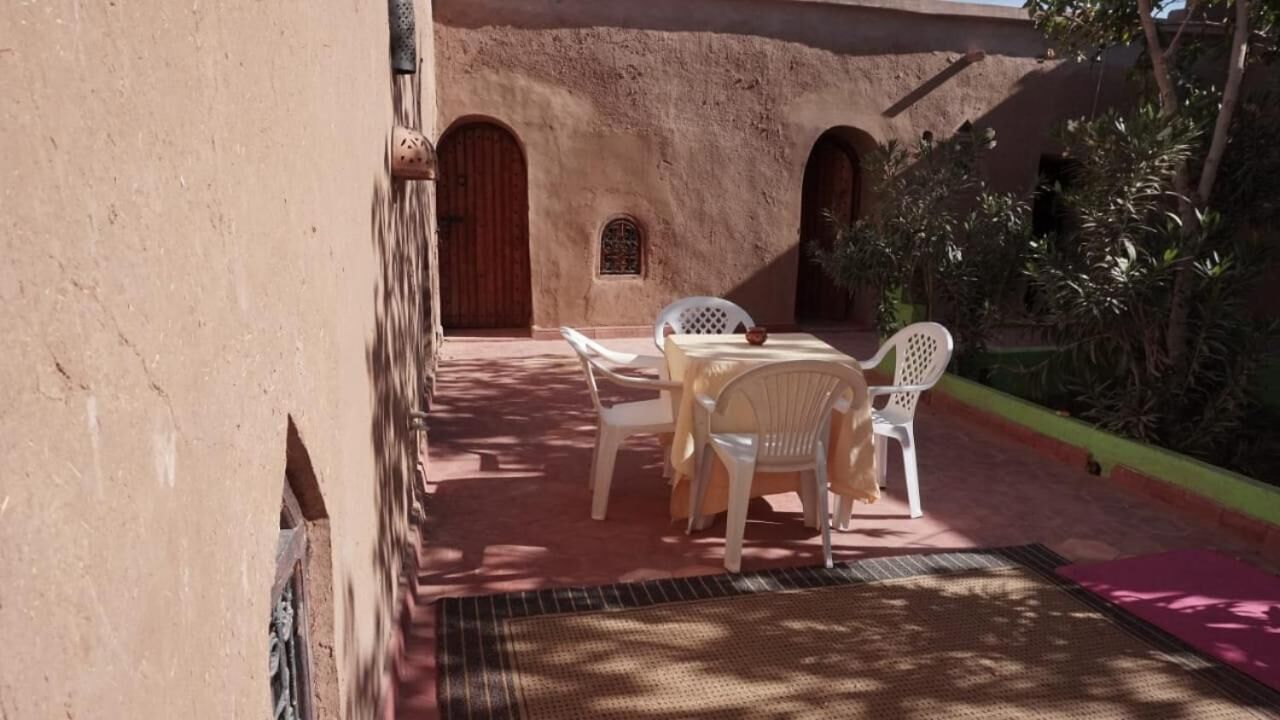 A courtyard with a table and chairs, a door, and a small window.