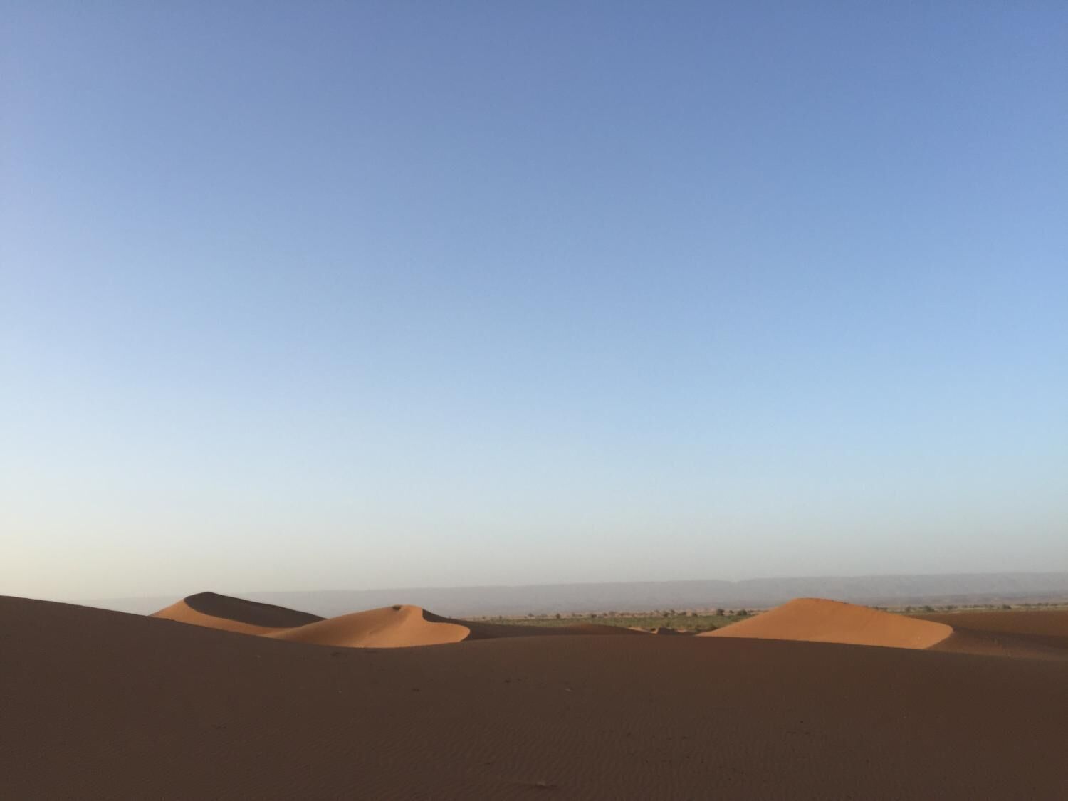 A desert landscape with sand dunes under a clear sky.