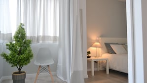 A bedroom with a bed, a bedside table with a lamp, a chair, and a small potted tree. - Downtown Porto Spot - 2 (Porto)