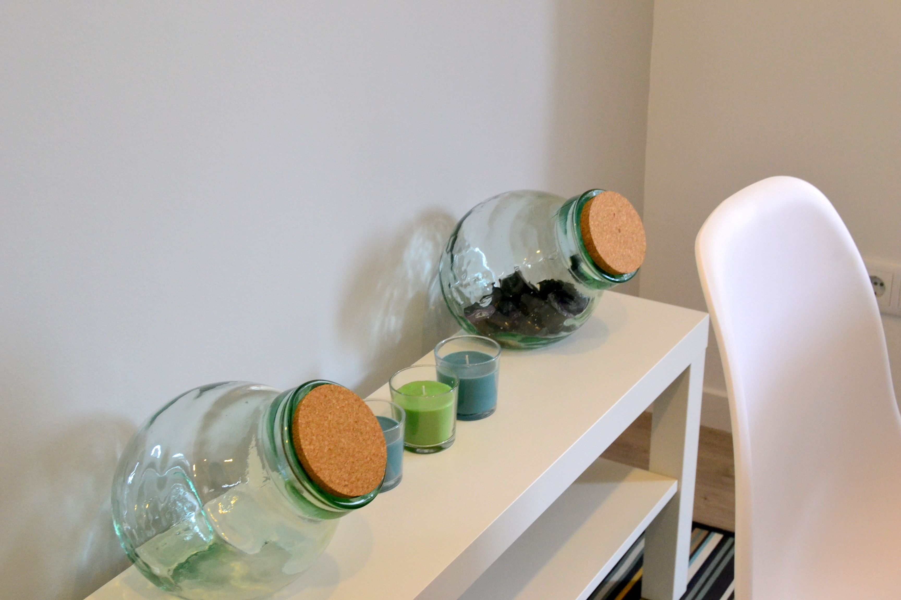 Two glass jars with cork stoppers on a white shelf.