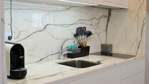 A kitchen with a marble countertop, a coffee machine, a sink, and a utensil holder. - Downtown Porto Spot - 2 (Porto)