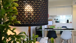 A modern kitchen with white cabinets, a glass dining table, and a black pendant light. - Downtown Porto Spot - 2 (Porto)