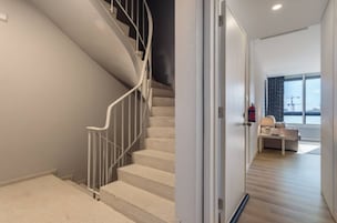 Um interior moderno com uma escada, um sofá e vista para o exterior.