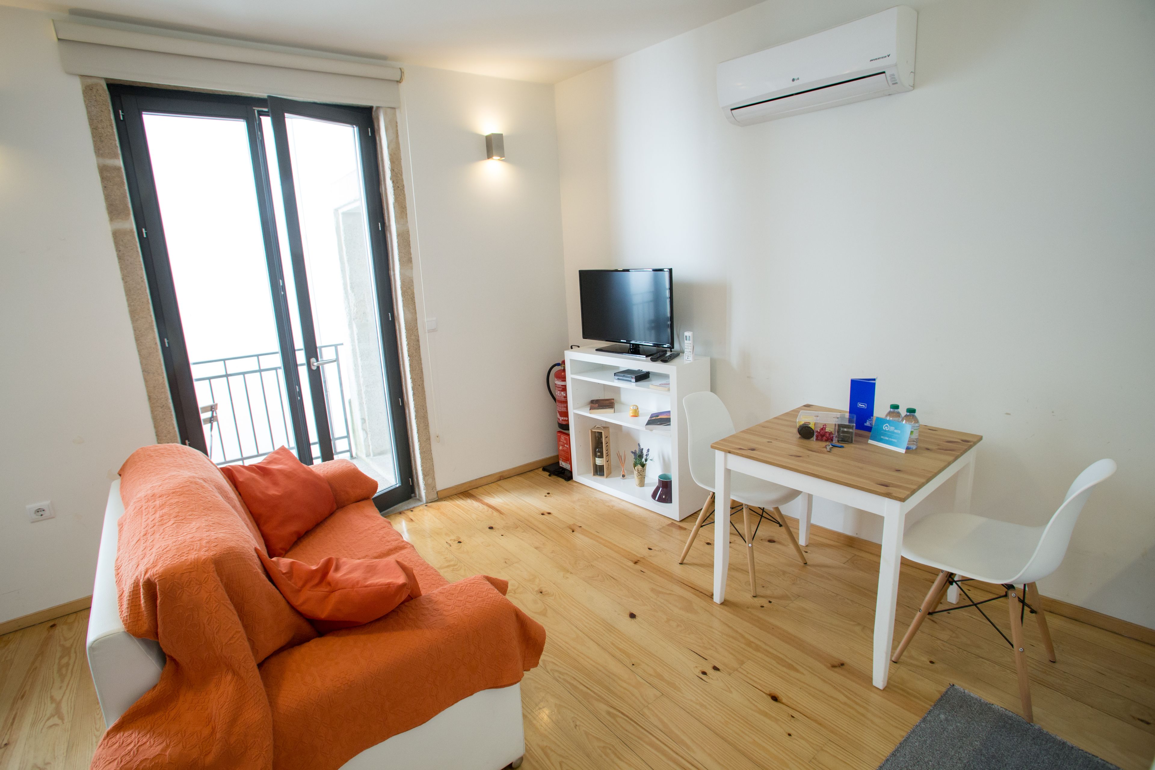 Ein modernes Wohnzimmer mit einer Couch, einem Fernseher, einem kleinen Tisch und einem weißen Sessel.