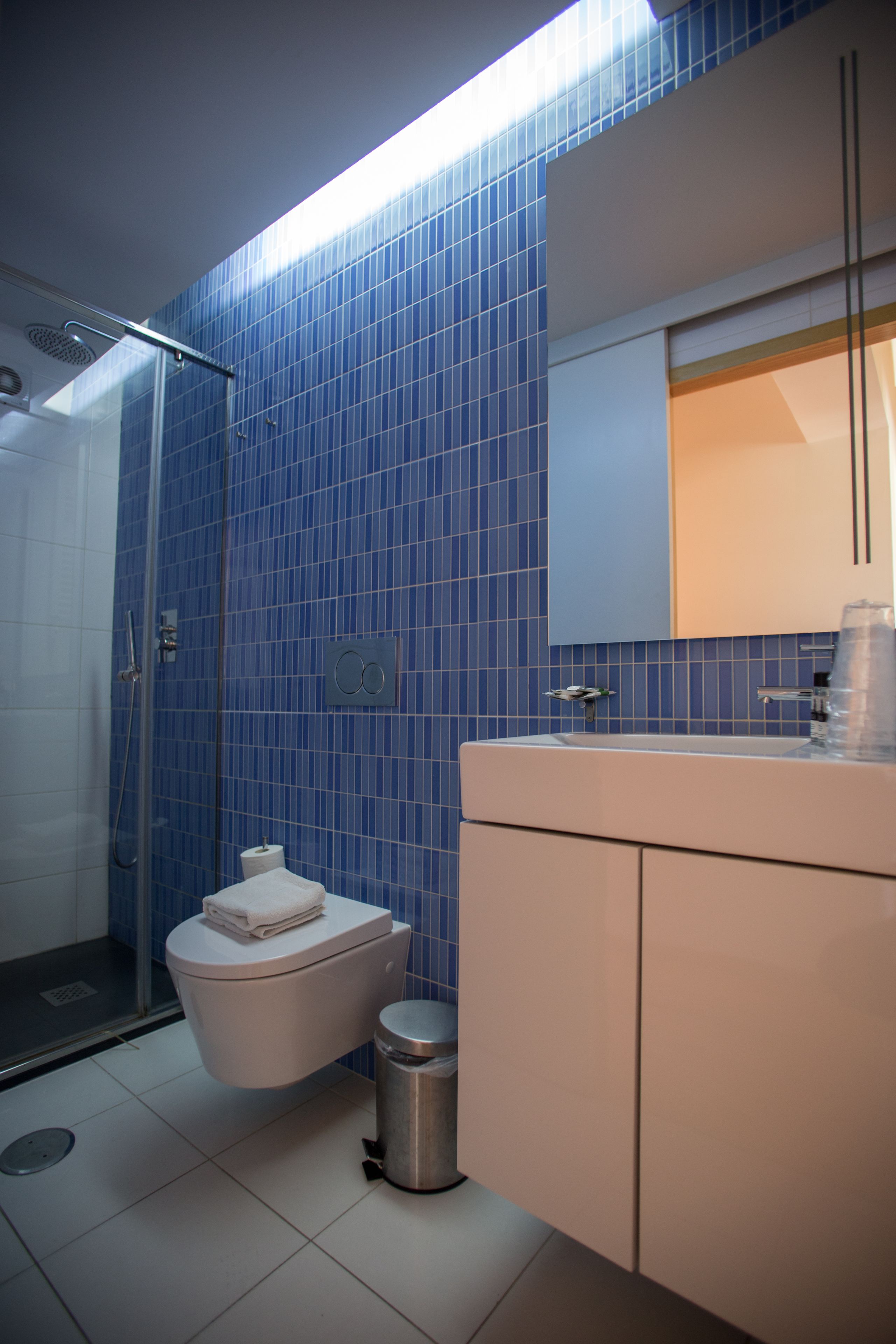 Une salle de bain avec une douche à parois de verre, des toilettes et un lavabo avec un miroir au-dessus.
