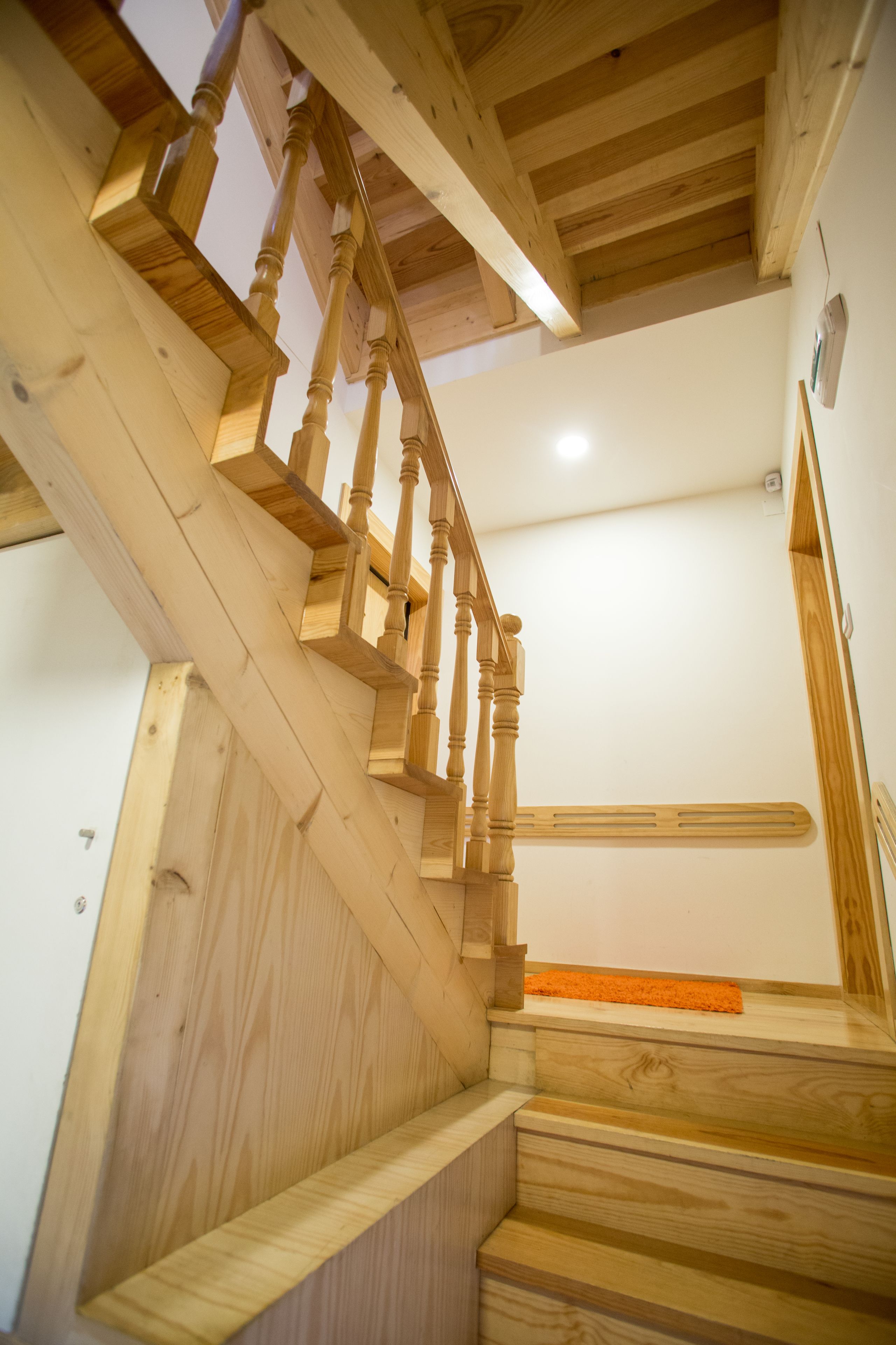 Una escalera de madera con barandilla y un rellano con alfombra.