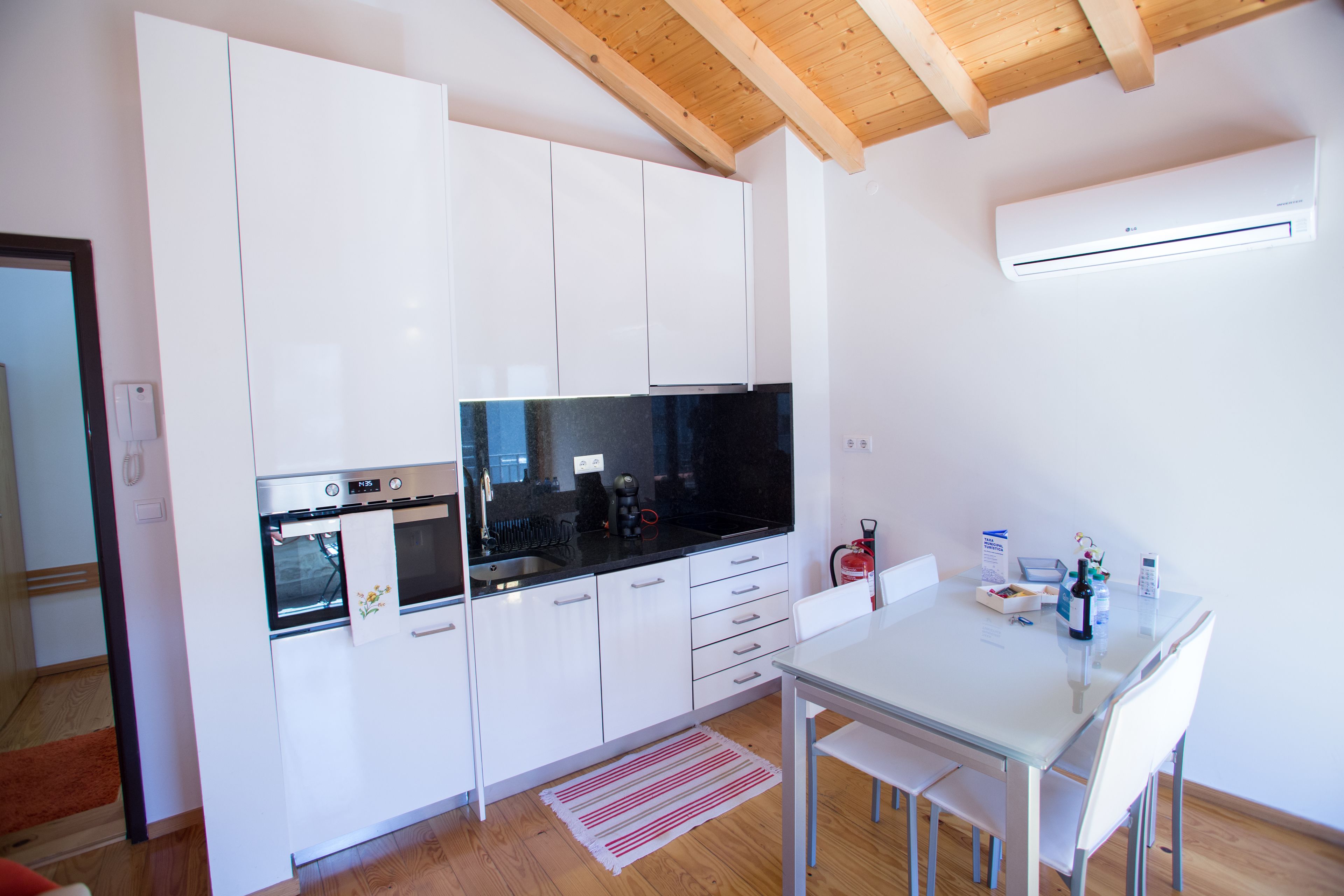 Una cucina moderna con mobili bianchi, un piano di lavoro nero e un soffitto in legno.