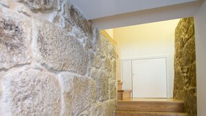 A staircase with stone walls and wooden steps leading to a door.