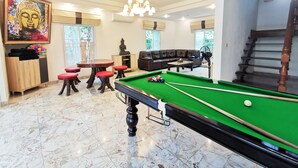 A billiards room with a pool table, a sofa, and a statue.