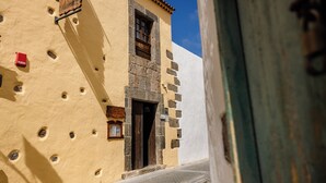 A narrow street with a building featuring a stone entrance and a wooden door. - Hotel Rural Casa de los Camellos (Aguimes)