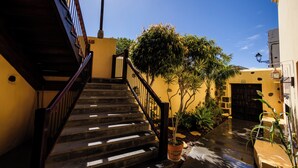 A staircase leading to a door, surrounded by potted plants and a clear blue sky. - Hotel Rural Casa de los Camellos (Aguimes)