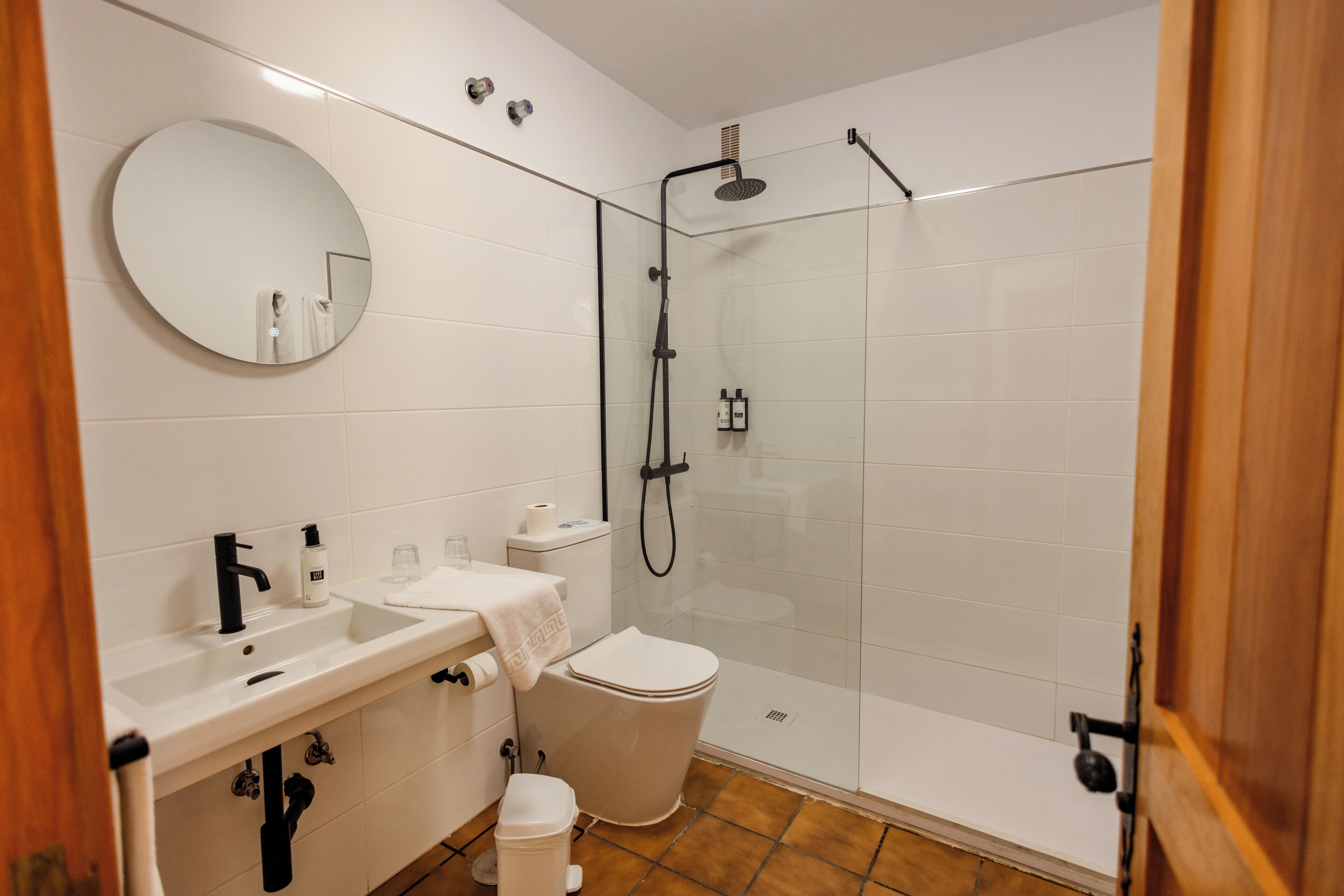 A bathroom with a sink, mirror, toilet, and glass-enclosed shower.