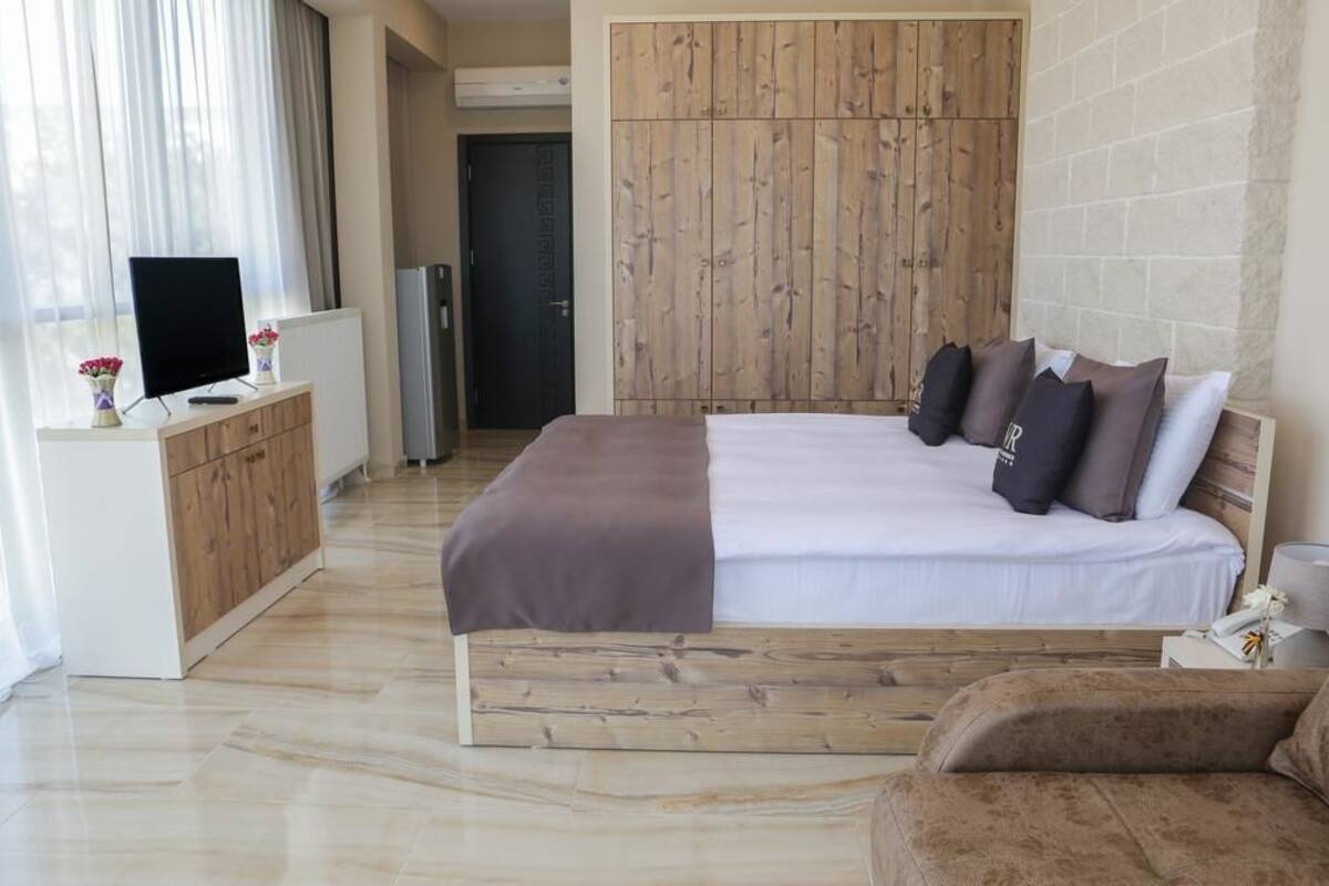 A bedroom with a bed, bedside table, and a TV on a dresser.