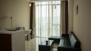 A modern living room with a black sofa, a glass coffee table, and a dining area with a white table and chairs. - Villa Residence Hotel (Tbilisi)