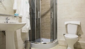 Une salle de bain avec une douche à parois de verre, un lavabo blanc et des toilettes.