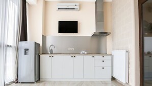 A modern kitchen with a built-in oven, a microwave, a sink, and a flat-screen TV mounted above the counter. - Villa Residence Hotel (Tbilisi)