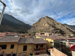 A mountainous village with traditional buildings, a prominent hill, and a sign for 'El Dorado Disco'. - Hostal Apu Qhawarina (Ollantaytambo)