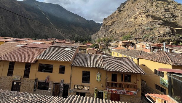 Un pueblo montañoso con edificios de tejas de arcilla, una montaña destacada al fondo y un letrero que dice 'EL DORADO'.