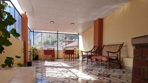 Un espacio interior amplio con suelo estampado, muebles de madera y ventanas grandes que ofrecen vistas al exterior.