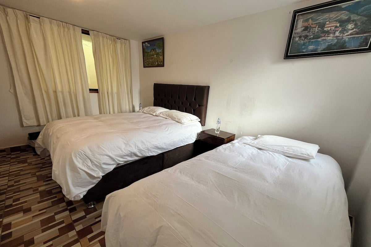 Ein Hotelzimmer mit zwei Betten, einem Kopfteil, einem Gemälde und einer Rezeption.