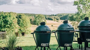 Three outdoor grills in a grassy area with a view of a forested landscape. - Tastecelebration Residence (Brosarp)