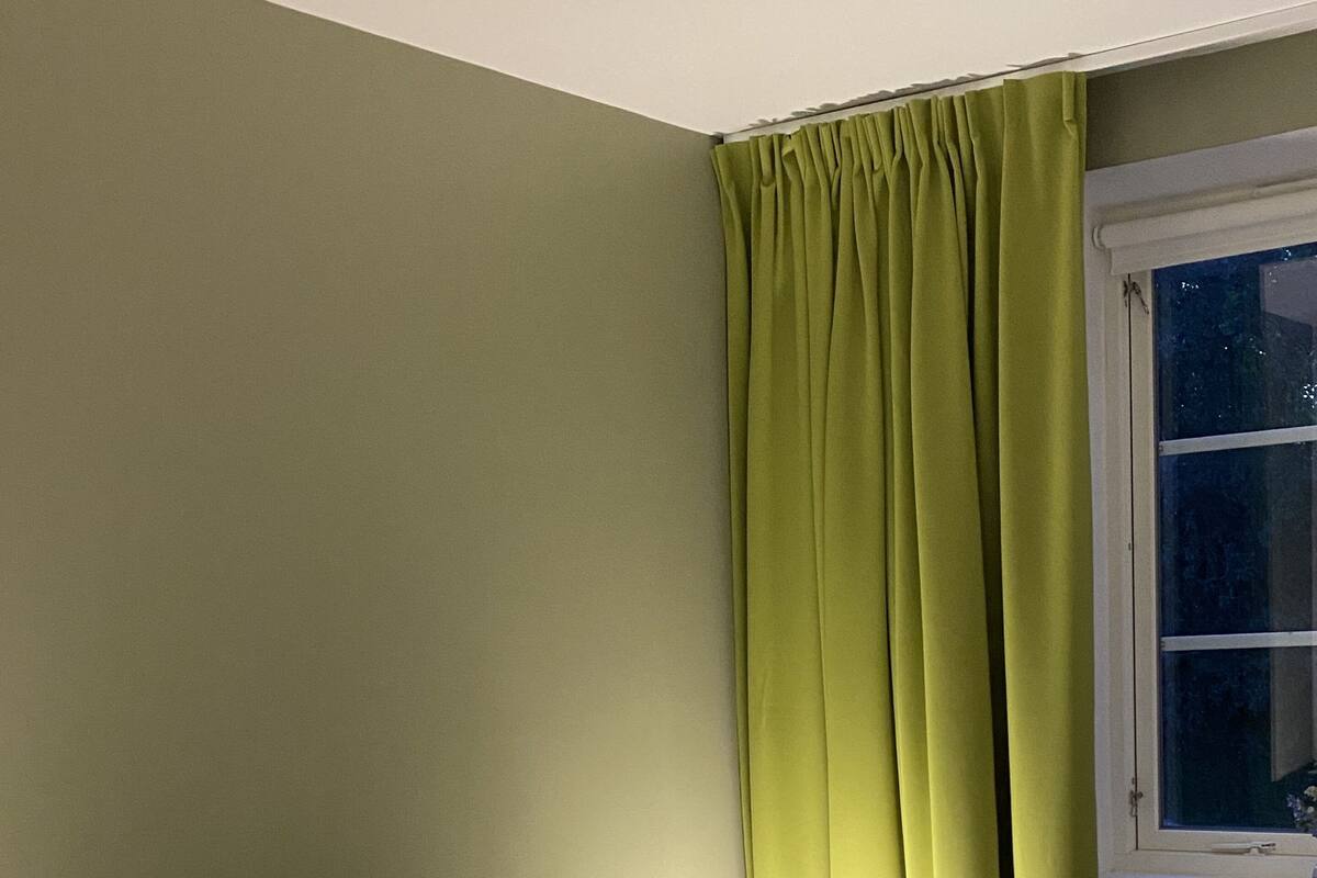 A bedroom with a bed, green curtains, and a window.