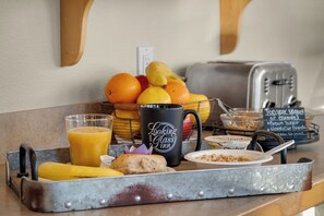A breakfast tray with fruits, a mug, a toaster, and a bowl of cereal.