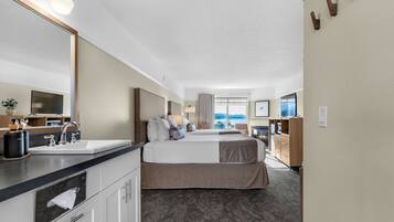 Habitación de hotel con una cama grande, baño con lavamanos y espejo, y vista al exterior.