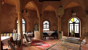 A traditional interior with high arched ceilings, patterned rugs, and a central table. - Jnane dar diafa (Tamegroute)
