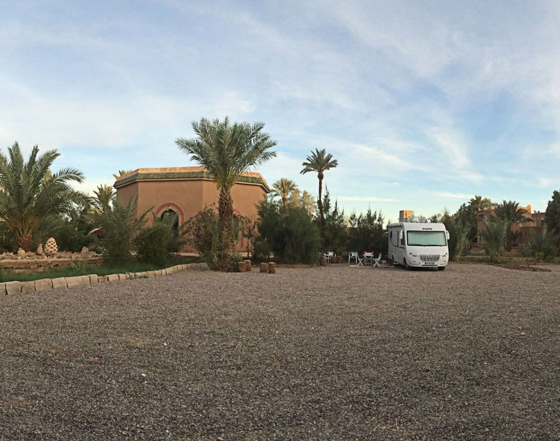 A gravel parking area with a white RV and a building with a dome roof.