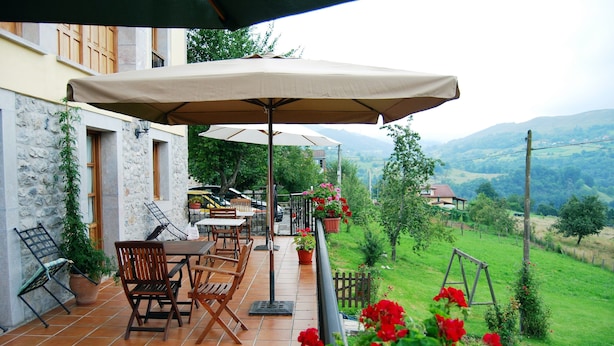 Une terrasse dotée de mobilier d’extérieur, d’une balançoire et offrant une vue sur la campagne.