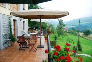 Une terrasse dotée de mobilier d’extérieur, d’une balançoire et offrant une vue sur la campagne.